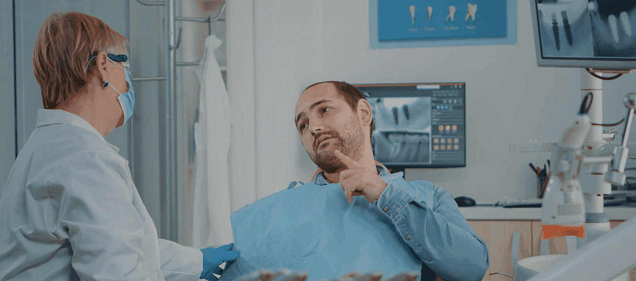 The dentist discusses orthodontic appliances with a patient seated comfortably in the dental chair, while X-rays illuminate the screen in the background in NYC