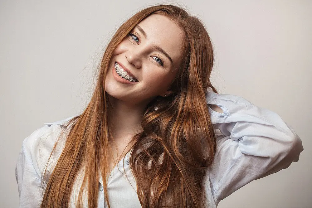 A woman smiles, showcasing adult orthodontics with braces in NYC