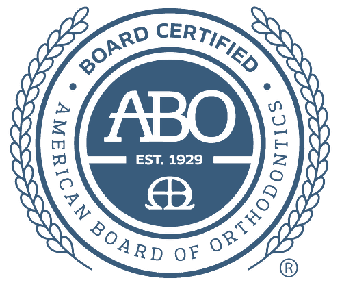 Blue seal logo of the American Board of Orthodontics, featuring "ABO" in the center, "Board Certified" and "Established 1929" text, enclosed by two wheat branches. Proudly displayed by a top orthodontist in NYC.