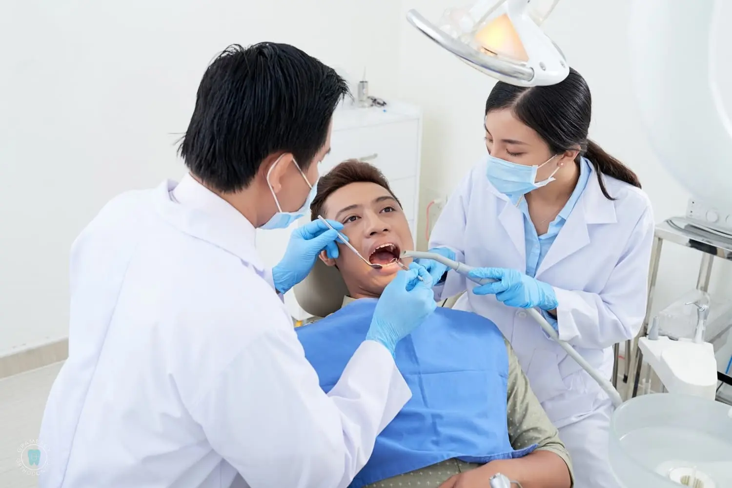 A dentist and assistant, both wearing masks and gloves, carefully assess the patient's oral health during a dental check-up, paying particular attention to any signs of tongue thrust in the clinic setting in NYC