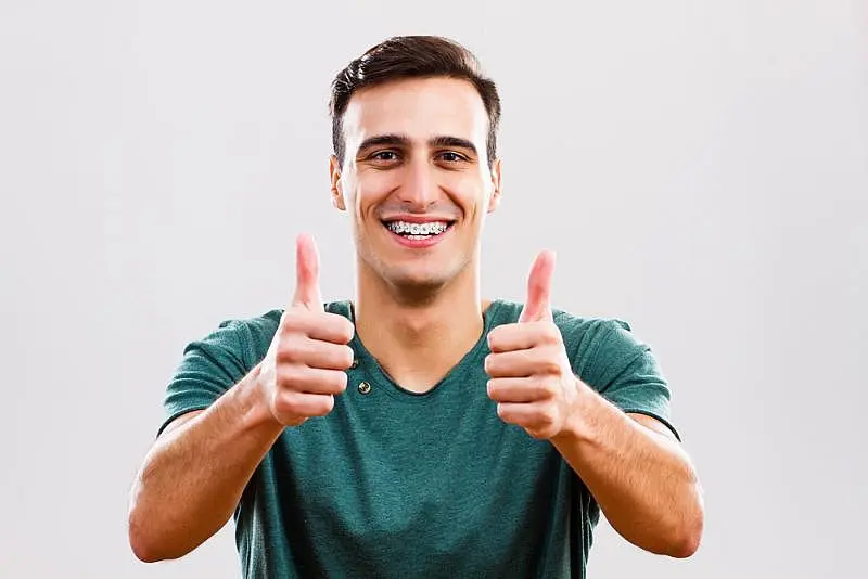A person with a bright smile, proudly showcasing their metal braces in NYC