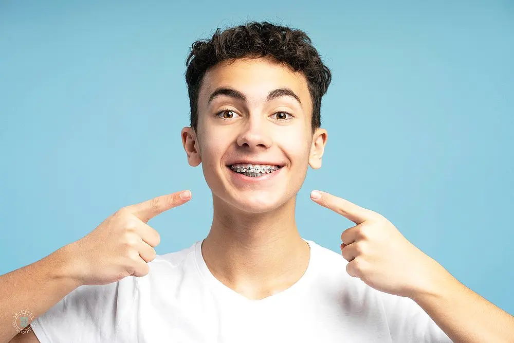 a boy pointing at his teeth with metal braces after considering between aligners vs braces in new york