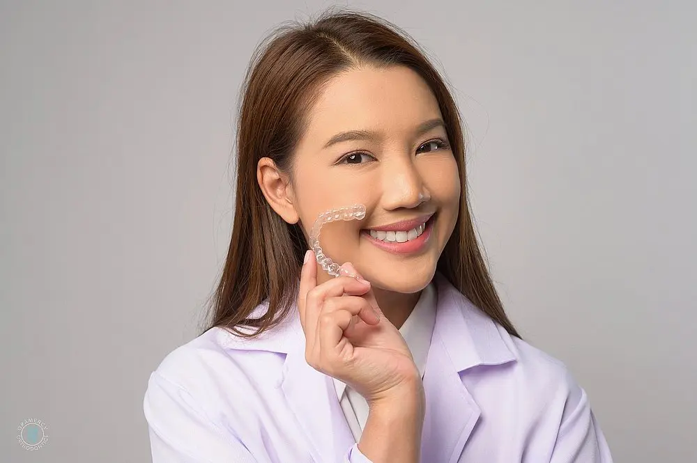 a young orthodontist holding invisalign clear aligners after explaining about aligners vs braces in new york