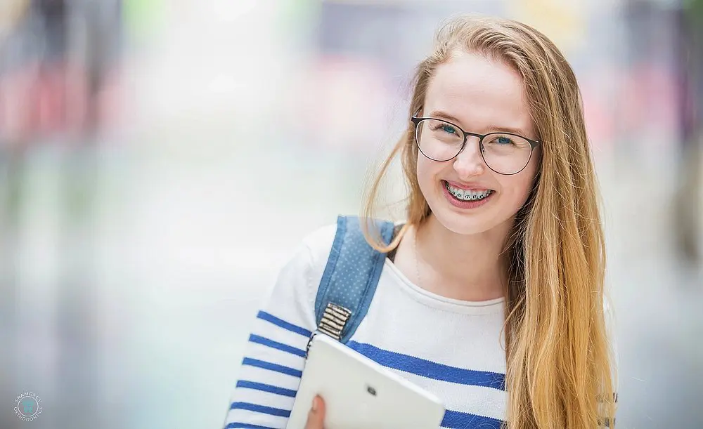 a school student woth braces smiling after learning how long do braces take in New York, NY