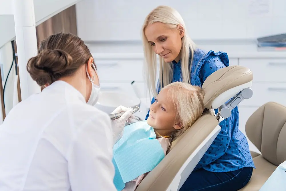 a mother watching an orthodontist taking care of her little daughters-teeth