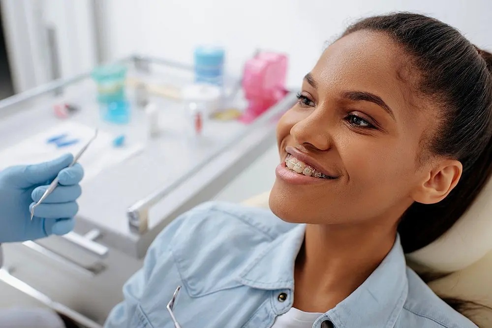 Smiling woman sitting in a dental chair during consultation – braces for overbite in New York, NY.