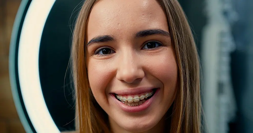 Close-up of a happy woman smiling in front of a mirror – braces for overbite in New York, NY.
