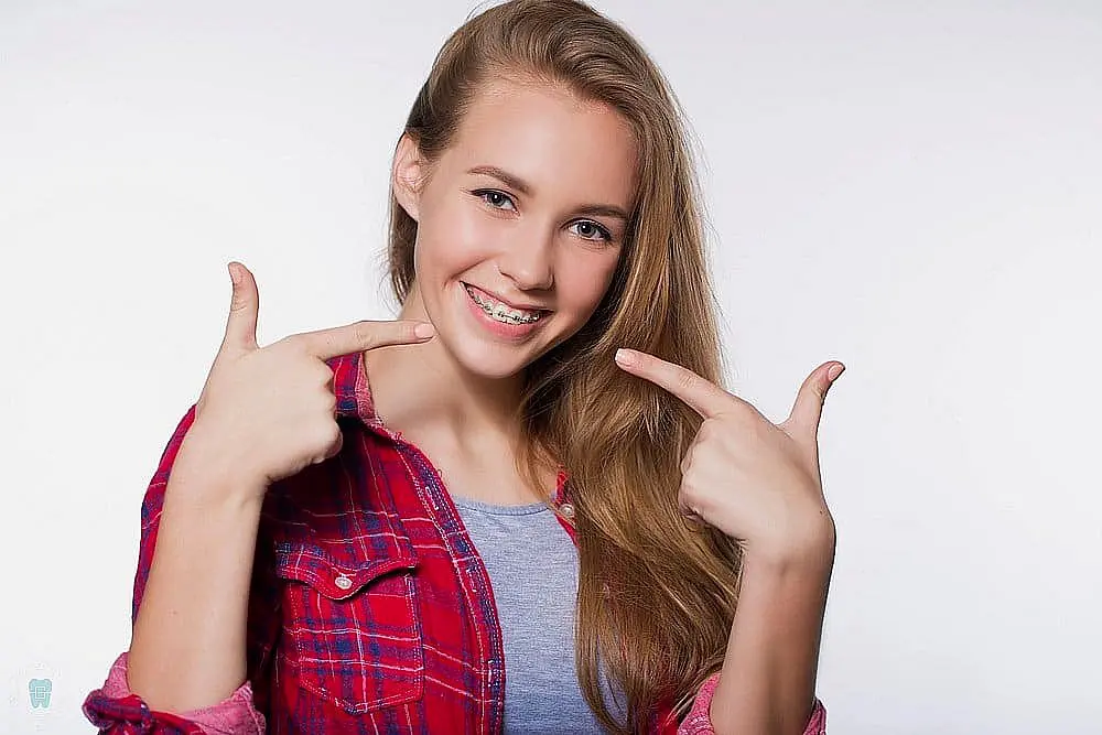 beautiful young blondie girl showing her metal braces isolated white - Clear Braces vs Metal Braces in New York CIty, NY 