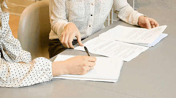 Two people are seated at a table, meticulously reviewing documents related to braces insurance, with one person thoughtfully holding a pen in NYC