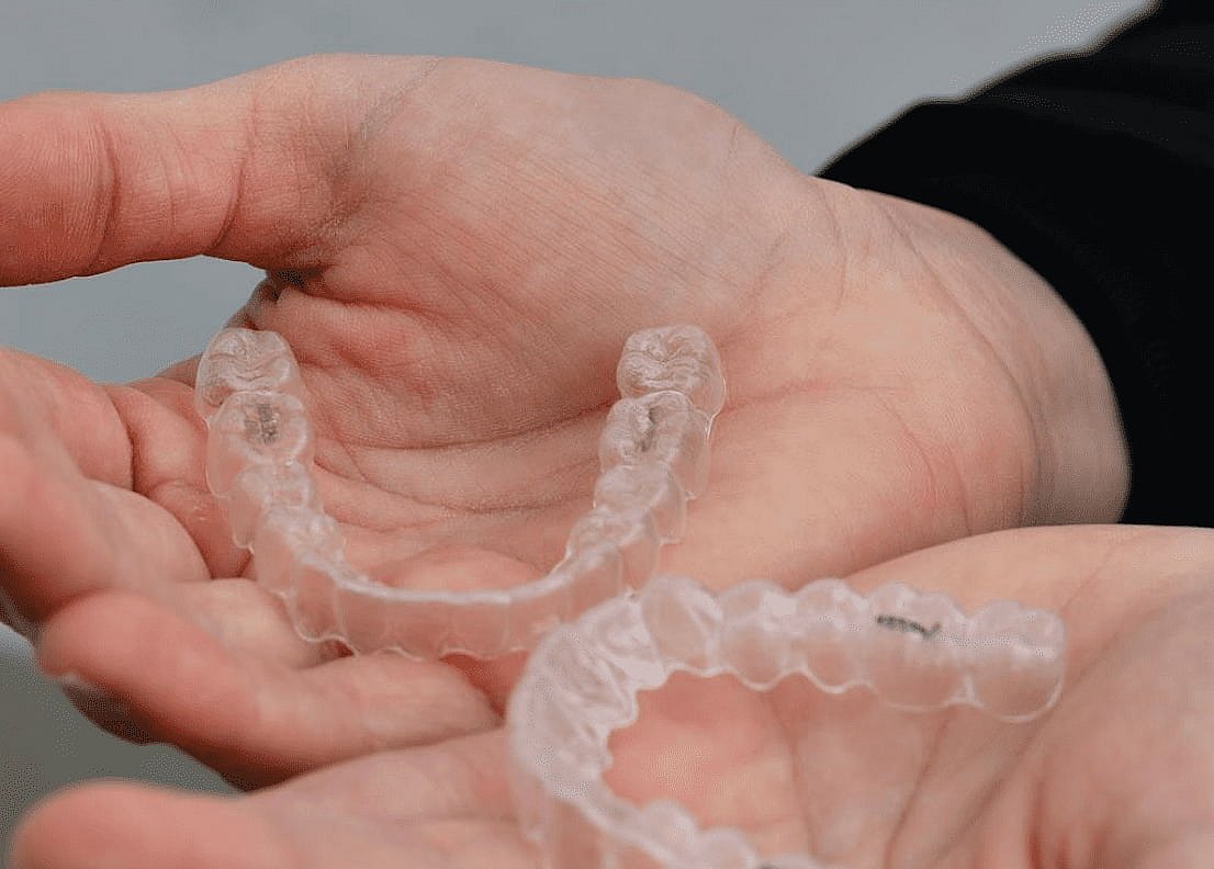 Two clear dental aligners are gently cradled in a person's hands, highlighting the precision of modern orthodontics. With an Invisalign payment plan, achieving your dream smile is now more accessible than ever in NYC